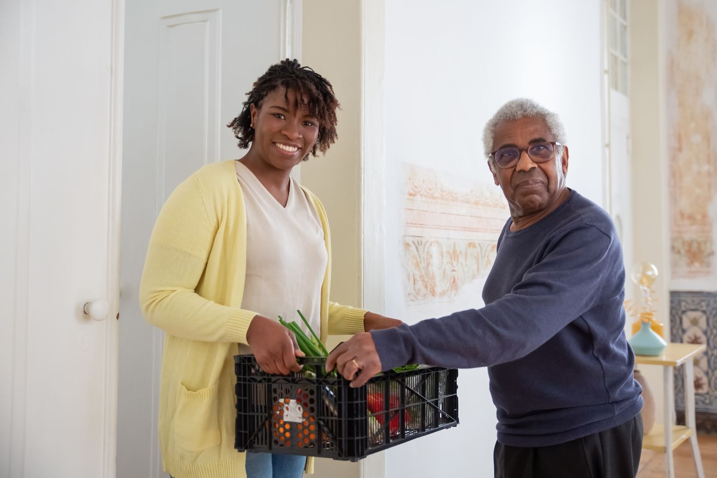A support worker helping a senior client in a bright home kitchen